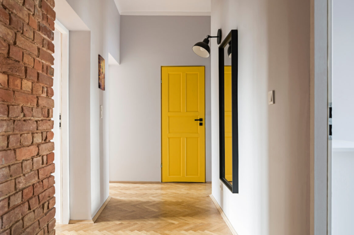 Puerta en el interior de la casa de color amarillo, paredes blancas y parquet