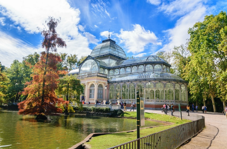 Imagen del palacio de cristal de Madrid entre la vegetación del Parque del Retiro