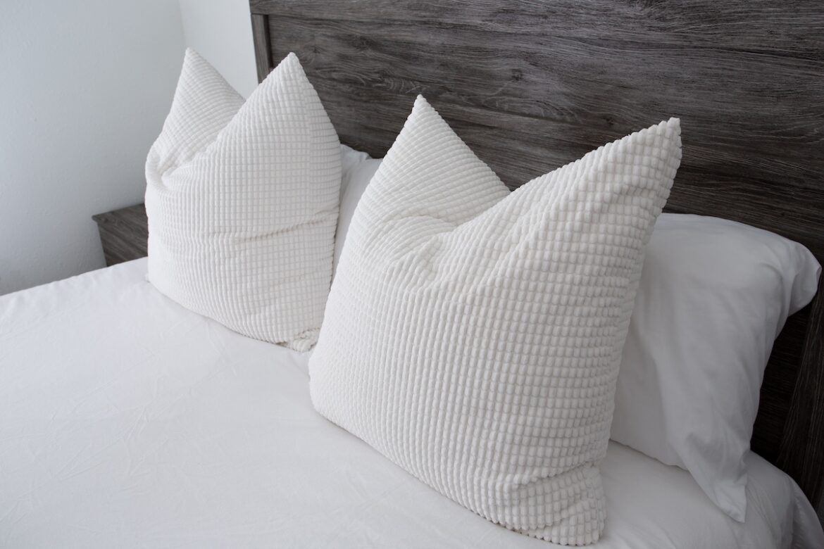 Almohadas blancas delante de un cabecero de madera oscura
