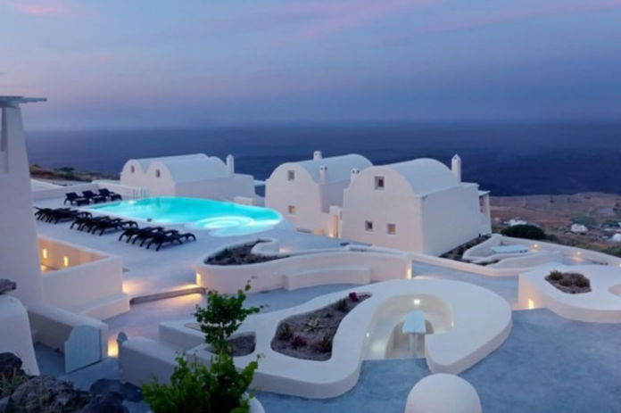 Cúpulas blancas y piscina iluminada al anochecer al estilo de las islas griegas