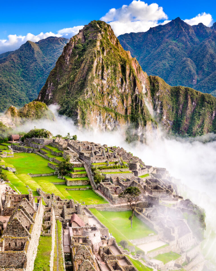 Imagen de la ciudad del Machu Picchu, una de las maravillas del mundo, con la montaña de fondo y nubes bajas